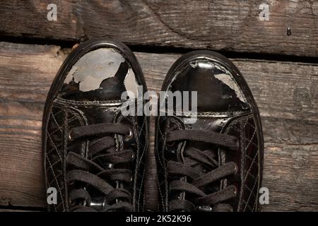 old patent torn shoes on a wooden floor, womens shoes, torn shoes Stock Photo