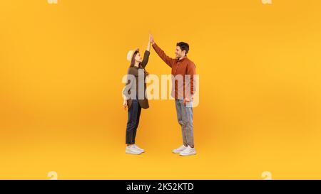 Happy Couple Giving High Five Celebrating Success Over Yellow Background Stock Photo