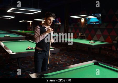 Portrait of young man preparing billiards cue Stock Photo