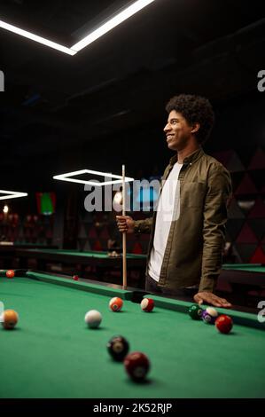 Portrait of young smiling man holding cue Stock Photo