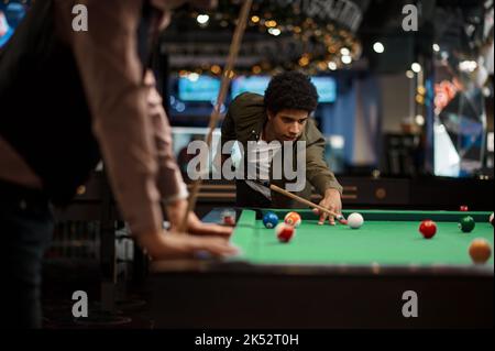 Company of handsome young guy playing in pool Stock Photo