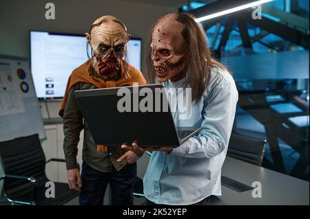 Two zombie businessmen looking at laptop screen Stock Photo