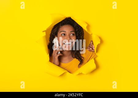 Black Lady Talking On Cellphone Posing In Hole In Paper Stock Photo