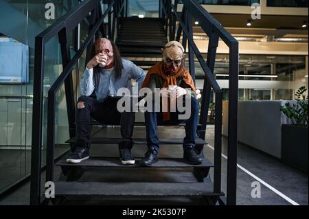 Zombie workers discussing online project on staircase Stock Photo