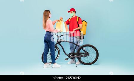 Deliveryman Giving Bags To Woman Delivering Parcel On Blue Background Stock Photo