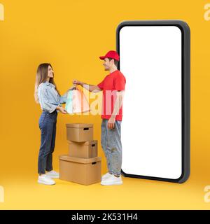 Courier Delivering Order To Female Standing Near Smartphone In Studio Stock Photo