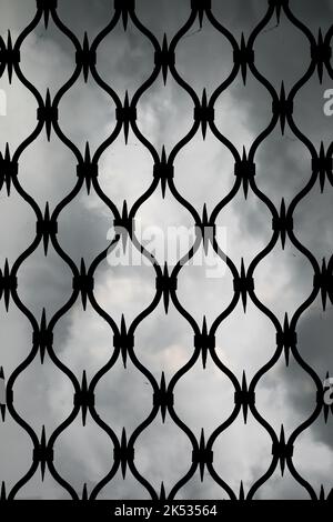Forged iron gates against the gray sky. An iron door grid background Stock Photo