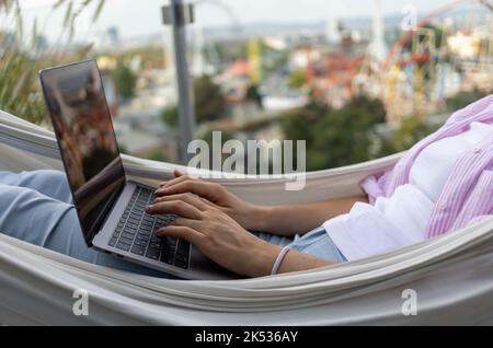 young woman freelancer working in hammock on terrace Stock Photo