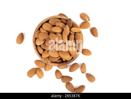 Top view of almond nuts grains in a wooden bowl and on a white background. Focus on the beans in the bowl. Copy space. Stock Photo