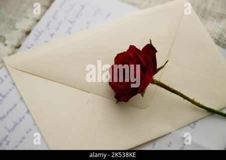 Image of a dry rose on a letter written by hand from a loved one in the past. nostalgic love concept Stock Photo