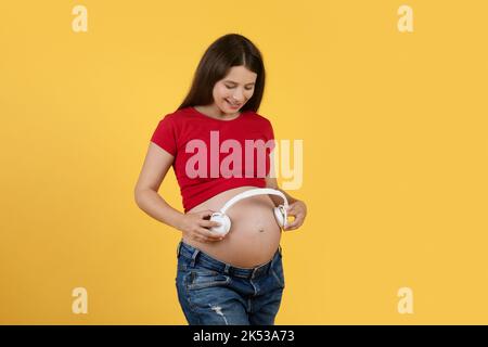 Pregnant Woman Holding Headphones Near Belly, Playing Melody To Baby in Womb  Stock Photo - Image of adult, family: 200049526