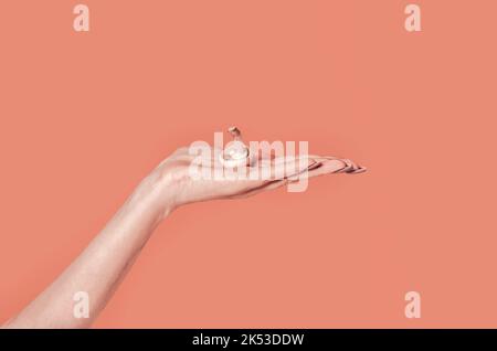 A simple minimalist autumn concept. A  beautiful woman's hand holds a brown mushroom in her palm. Tawny orange background. Simple modern nature backgr Stock Photo