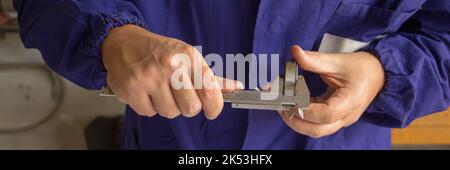 Image of the hands of a mechanic measuring a ball bearing with a caliper. Precision mechanics. Horizontal banner Stock Photo