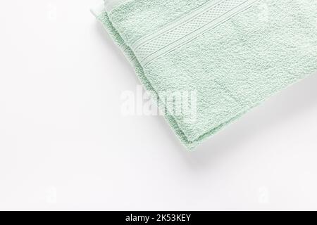 New folded mint green bath sheet or towels on white background. Top view, copy space Stock Photo