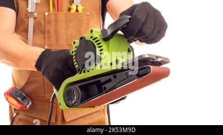 Carpenter in workers apron holding belt electric sander on white background Stock Photo