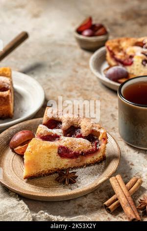 Plum pie pieces or The New York Times Famous Plum Torte with spices and tea on textured background, recipe in rustic style Stock Photo