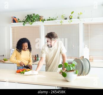 Young multi-ethnic couple in the kitchen while cooking and cleaning. Stock Photo