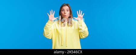 Imagine this. Excited and happy outgoing blond girl explain something and gesturing, holding hands near face, showing number ten, talking to camera Stock Photo