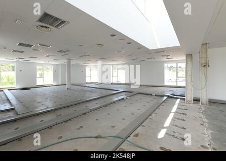 Empty industrial warehouse with concrete floors, waiting for new coverage with large windows and white technical ceiling and metal gutters Stock Photo