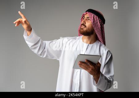 Arab businessman using digital tablet on gray background Stock Photo
