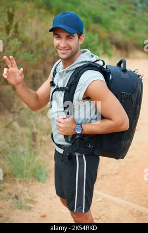 Waving wanderer. Handsome young hiker waving at the camera - portrait. Stock Photo