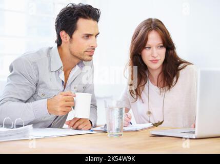 Going over the final design. a two young design professionals sitting together and discussing something on a laptop. Stock Photo