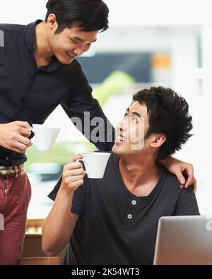 Heres to our future. a young gay couple drinking coffee while sitting with a laptop. Stock Photo