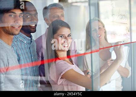 They plan as a team. Portrait of a group of businesspeople writing down their plans on a glass pane. Stock Photo