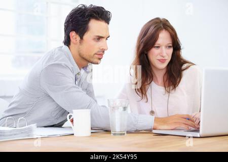 This looks a bit off...a two young design professionals sitting together and working on a laptop. Stock Photo