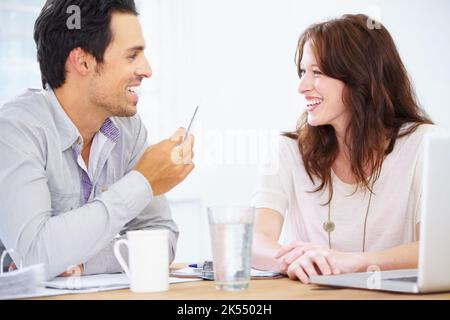Enjoying a moment away from work. a two happy-looking young design professionals sitting together and discussing something on a laptop. Stock Photo
