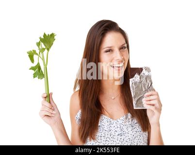 Chocolate for the win. An attractive young woman choosing between a stick of celery and a slab of chocolate. Stock Photo