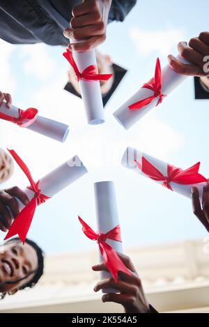 Graduation, diploma and hands with a student group outside in a huddle or circle from below. Graduate, success and university with friends holding a Stock Photo