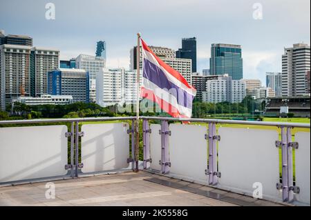 The Thailand flag flies on the platform of the BTS mass transit sky train station of Ratchadamri, Bangkok, Thailand. Stock Photo