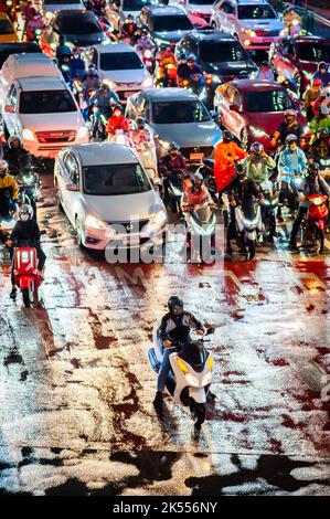 Traffic waits at the zebra crossing at the famous busy Asoke Montri Rd. road junction in Bangkok, Thailand on a wet rainy evening. Stock Photo