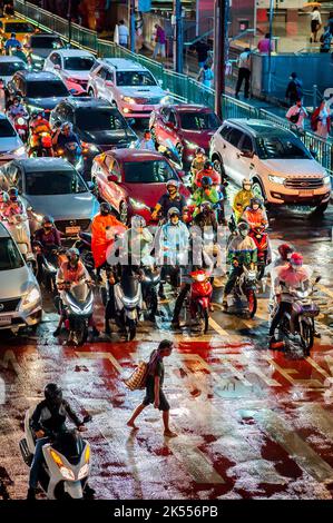 Traffic waits at the zebra crossing at the famous busy Asoke Montri Rd. road junction in Bangkok, Thailand on a wet rainy evening. Stock Photo