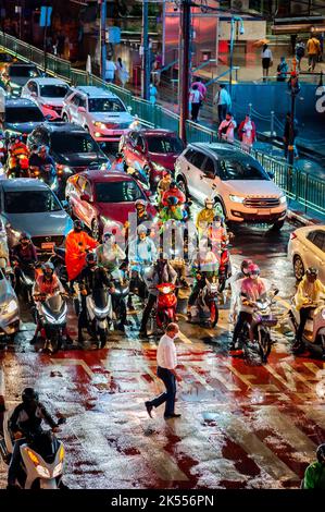 Traffic waits at the zebra crossing at the famous busy Asoke Montri Rd. road junction in Bangkok, Thailand on a wet rainy evening. Stock Photo