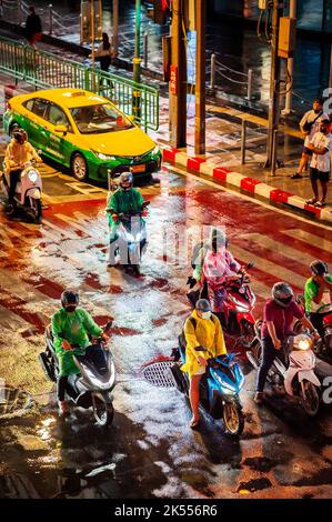 Traffic waits at the zebra crossing at the famous busy Asoke Montri Rd. road junction in Bangkok, Thailand on a wet rainy evening. Stock Photo