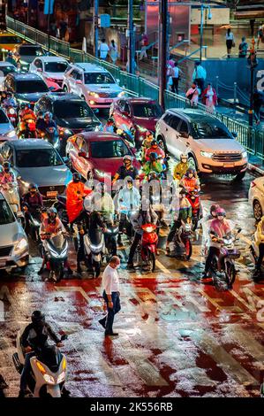 Traffic waits at the zebra crossing at the famous busy Asoke Montri Rd. road junction in Bangkok, Thailand on a wet rainy evening. Stock Photo