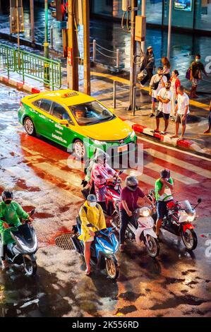 Traffic waits at the zebra crossing at the famous busy Asoke Montri Rd. road junction in Bangkok, Thailand on a wet rainy evening. Stock Photo