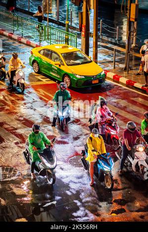 Traffic waits at the zebra crossing at the famous busy Asoke Montri Rd. road junction in Bangkok, Thailand on a wet rainy evening. Stock Photo