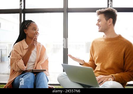 Friends, diversity and student friends talking and speaking together with technology. University students in a discussion chatting about education and Stock Photo