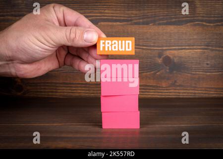 Fraud concept. Colorful wooden blocks in a pile on a textured background. Stock Photo