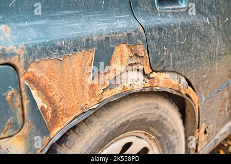 Fragment of an old damaged and rusted car. Vehicle body metal corrosion. Stock Photo