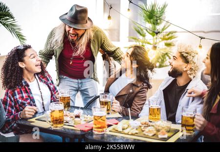 Multiracial guys and girls drinking beer pints at balcony patio - Youth social gathering life style concept on happy people enjoying hangout time toge Stock Photo