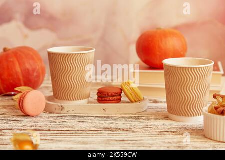 Aesthetics cardboard cups with pumpkin latte. Seasonal couple breakfast with coffee and macaroons among pumpkins. Cozy autumn atmosphere. Stock Photo