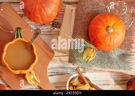 Aesthetic seasonal pumpkin latte in cup shape of pumpkin among pumpkins and leaves. Lagom, cozy autumn home. Stock Photo