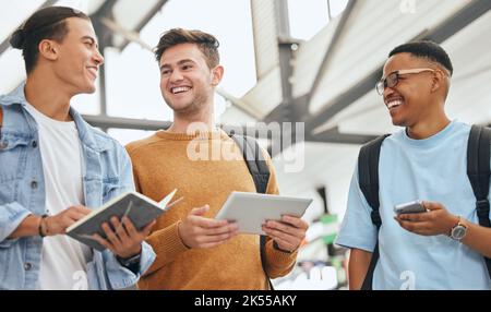Friends, university and students at campus, talking and planning a group assignment on digital tablet and sharing notes. Education, diversity and men Stock Photo