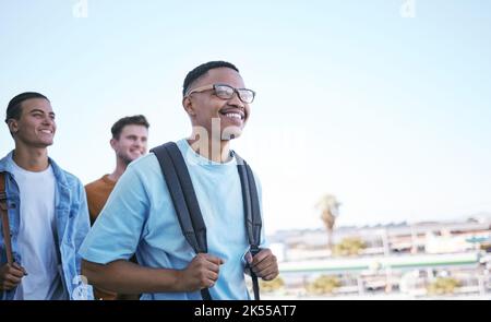 Student, education or travel with a man and friends walking to class on university or college campus as exchange students. Study, scholarship and Stock Photo
