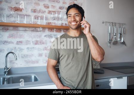 Happy, smile and man on a phone call in the kitchen of his home talking on technology for communication. Happiness, young and man from colombia having Stock Photo