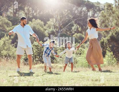 Freedom, happy family and fun in a park with black children and parents bonding and playing on grass. Love, energy and kids excited and happy while Stock Photo